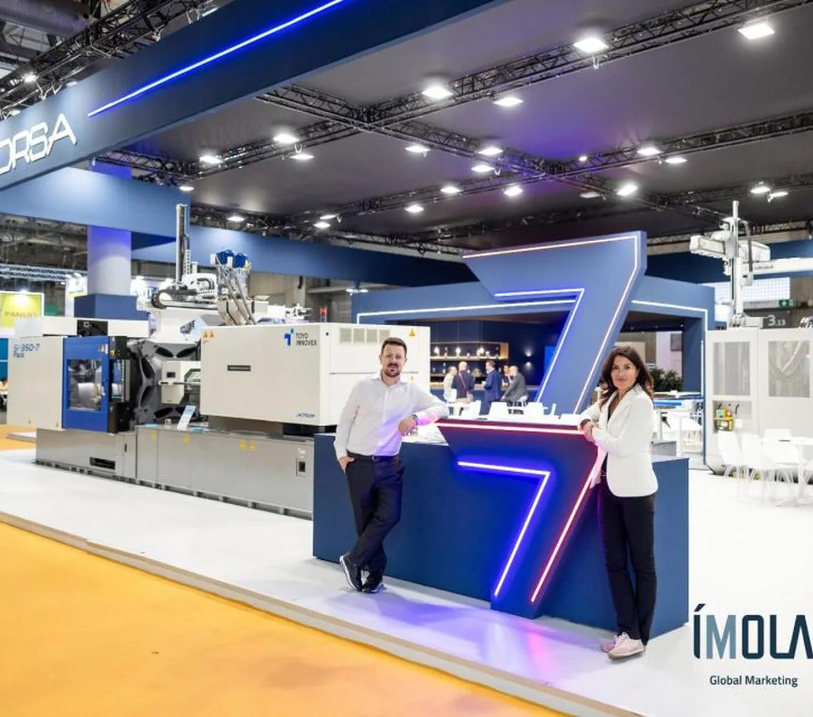Frontal del stand de Raorsa en Equiplast, con el gran número 7 y dos asistentes
